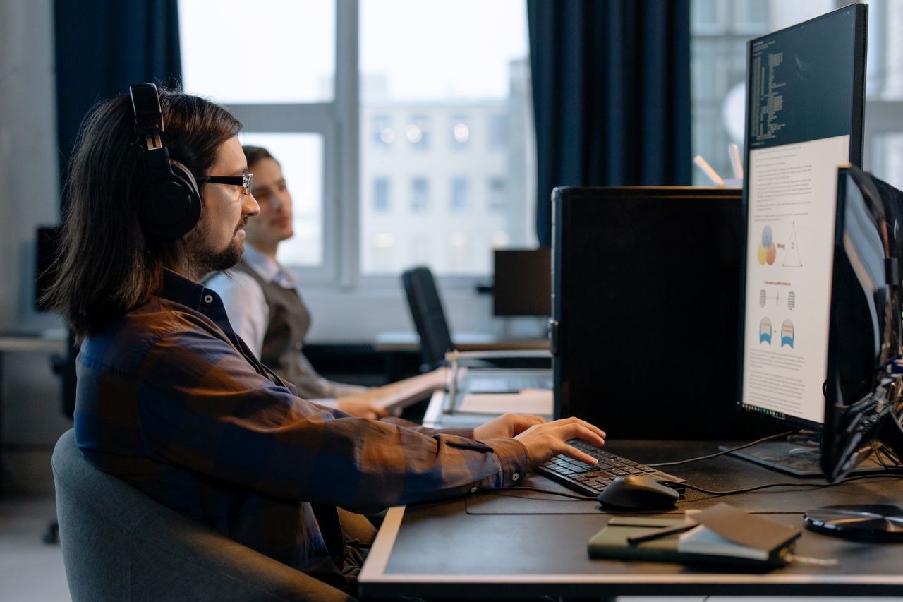 services-02 Two programmers working together with focus on coding in a modern, tech-savvy office environment.